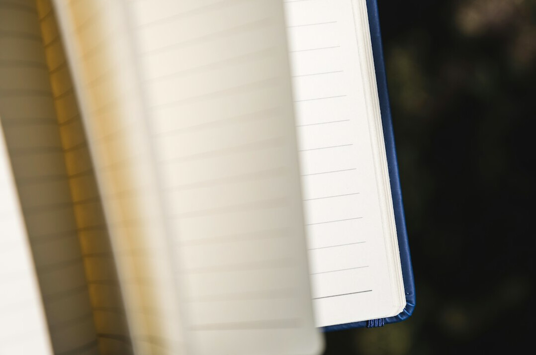 Close up of a hand writing notes in a notebook with a pen